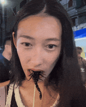 a woman is eating a scorpion on a stick with an adidas logo in the background