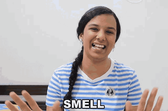 a woman wearing a blue and white striped shirt with the word smell on her chest