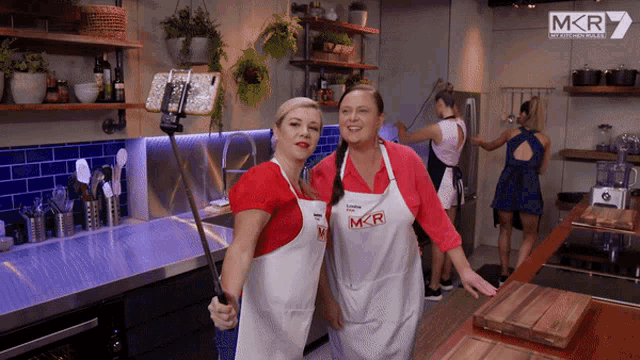 two women wearing aprons that say mkr pose for a picture
