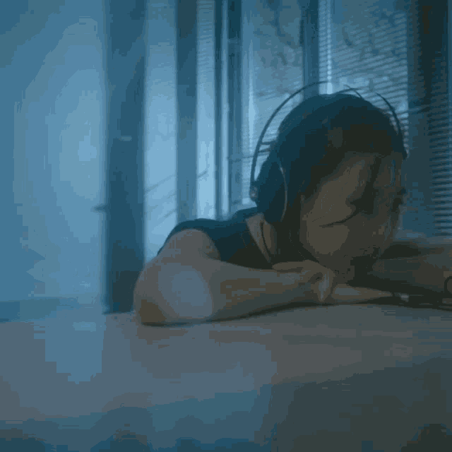 a woman wearing headphones is laying on a desk
