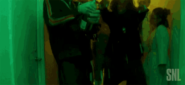 a group of people are dancing in a room with a green light .