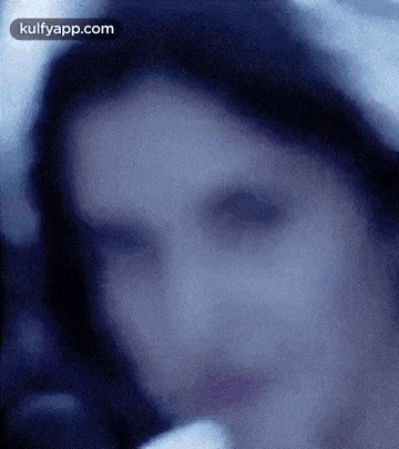 a close up of a woman 's face in a blurry photo with a blue background .