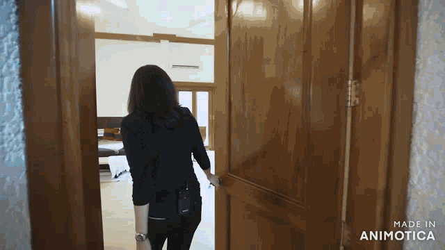a woman opens a wooden door with the words made in animatica on the bottom