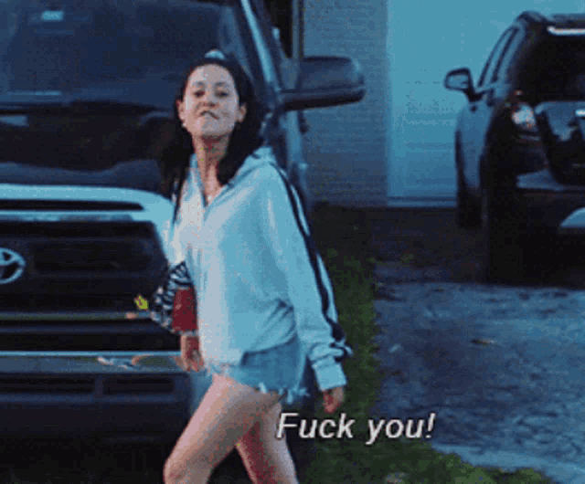 a woman walking in front of a toyota truck with the words fuck you on the bottom