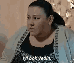 a woman is sitting in a chair with the words `` iyi bok yedin '' written next to her .