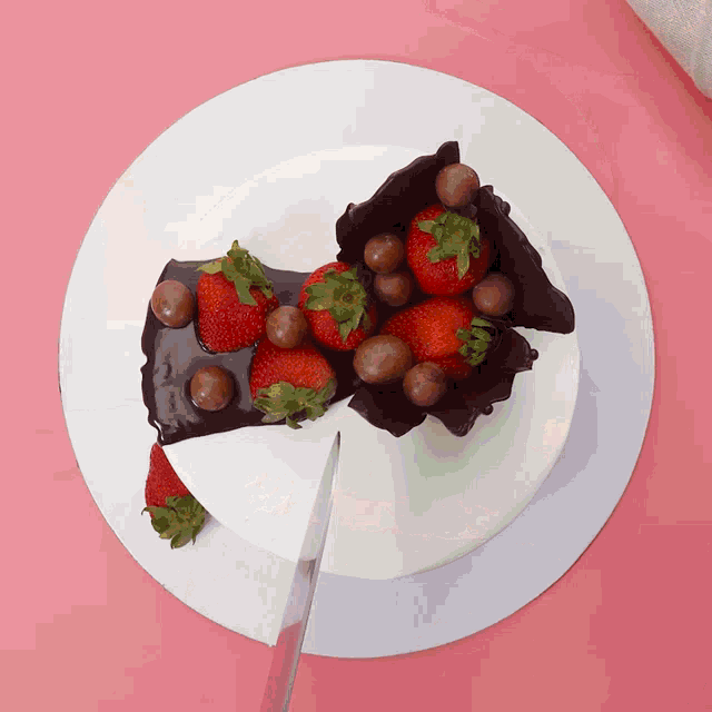 a white plate topped with chocolate covered strawberries and a slice taken out of it