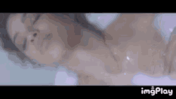 a woman is laying in a bathtub with her eyes closed and foam coming out of her chest .
