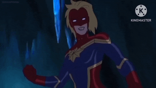 captain marvel is holding a purple ring in her hand while standing in a cave .
