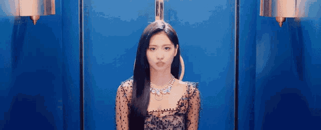 a woman with long black hair and a necklace is sitting in an elevator .