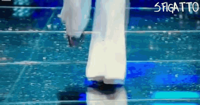 a woman in a white dress is walking down a staircase with the word figatto written on the bottom right