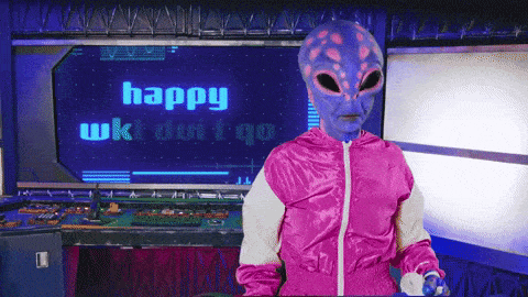 an alien in a pink jacket is sitting in front of a screen that says happy wkt duit qq
