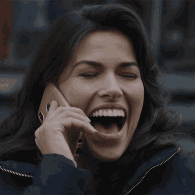 a woman is laughing while talking on a phone