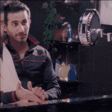 a man is washing his hands in front of a mirror with a bottle of soap on the shelf behind him