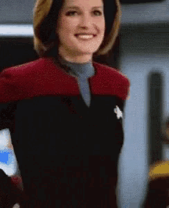a woman in a star trek uniform is smiling and looking at the camera .