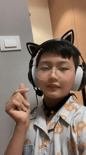 a person wearing headphones and glasses is making a heart shape