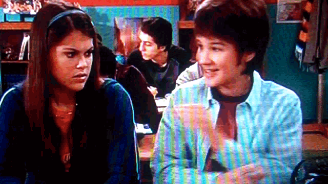 a girl and a boy are sitting next to each other in a classroom .