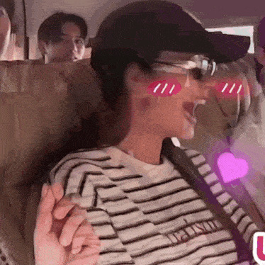 a woman wearing sunglasses and a hat is sitting in the back seat of a car holding a man 's hand .