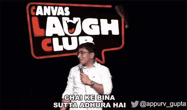 a man is giving a speech in front of a canvas laugh club sign