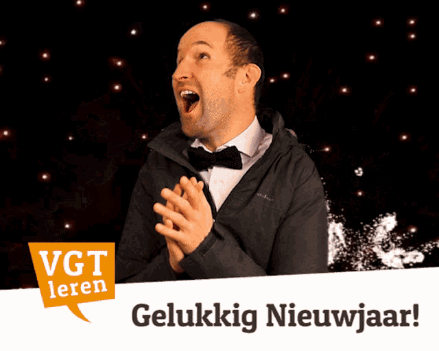 a man in a tuxedo is clapping in front of a sign that says gelukkig nieuwjaar