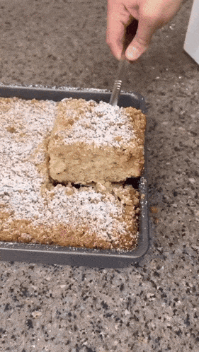 a person is cutting a piece of cake with powdered sugar on top