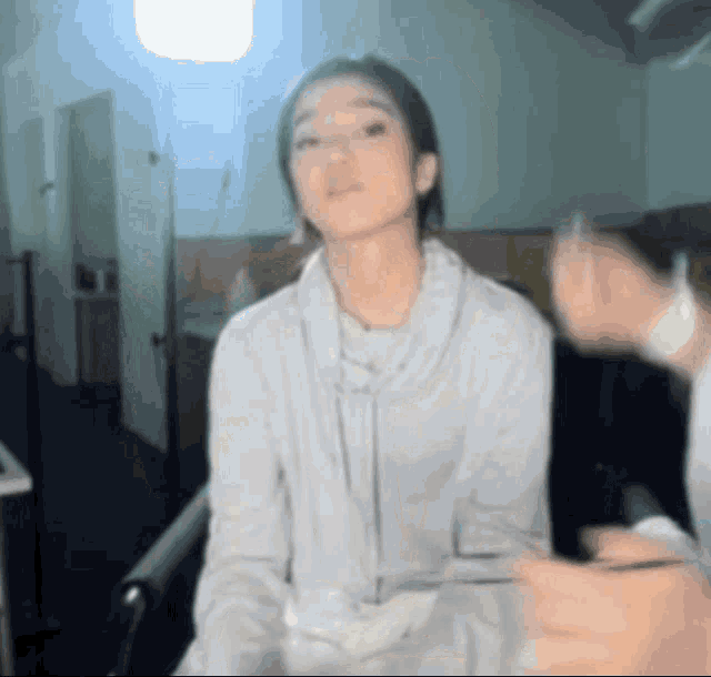 a woman in a white sweater is being held by someone