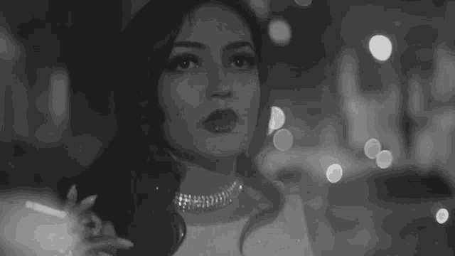 a black and white photo of a woman smoking a cigarette in a dark room .