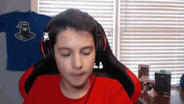a boy wearing headphones in front of a window with a blue shirt in the background