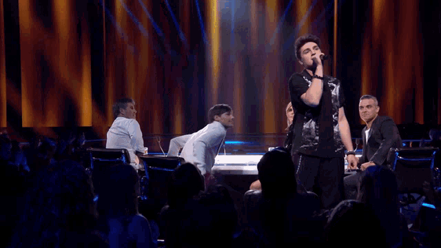 a man singing into a microphone on a stage