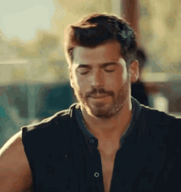 a man with a beard is wearing a black shirt without a shirt on .