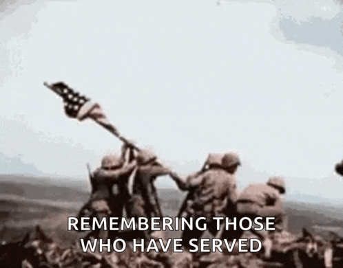 a group of soldiers raising an american flag in the air .