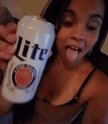 a woman is sticking out her tongue while holding a can of lite beer