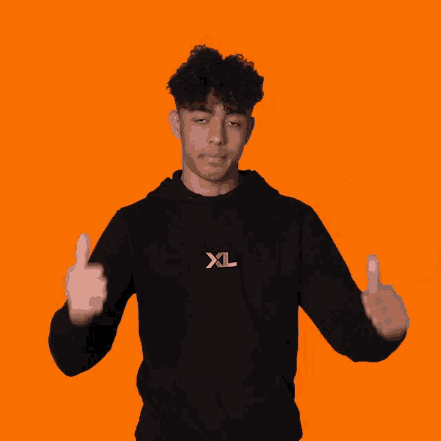 a young man wearing a black xl hoodie is making a thumbs down gesture