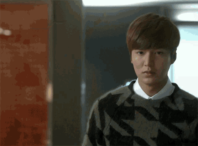 a young man wearing a black and white sweater with a geometric pattern