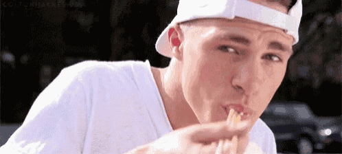 a man in a white hat is eating a sandwich .