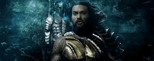 a man with a beard is holding a trident in a dark cave .