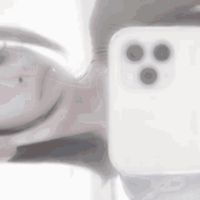 a blurry picture of a person taking a selfie with a white cell phone .