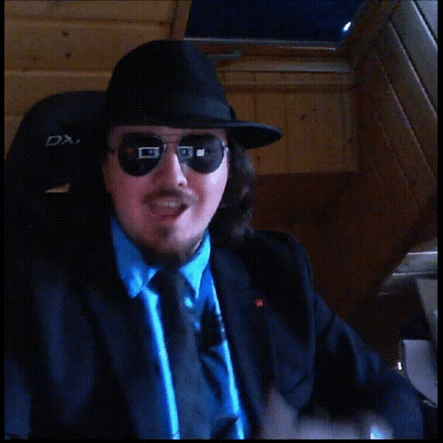 a man wearing a hat and sunglasses is giving a thumbs up sign