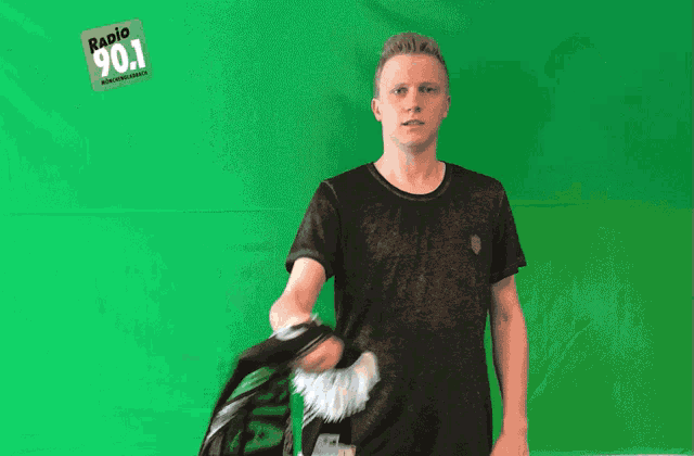 a man standing in front of a green screen with a radio 90.1 logo on it