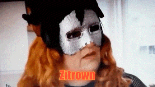 a woman with red hair is wearing a mask and the word zitrown is written in orange .
