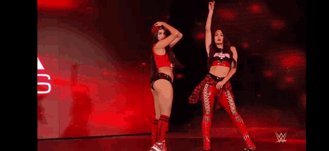 a couple of women are standing next to each other on a stage and dancing .