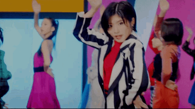a woman in a striped jacket is dancing in front of a group of other women