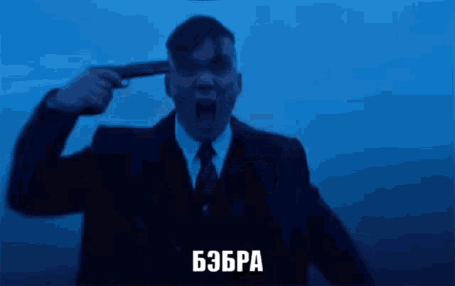 a man in a suit and tie is holding a gun to his head and screaming .