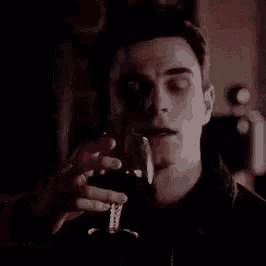 a man is holding a glass of wine in his hand .