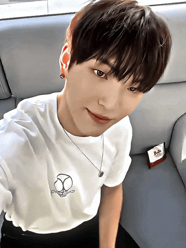 a young man wearing a white t-shirt with a skull on it is taking a selfie