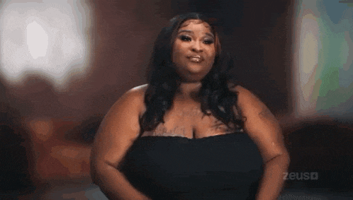 a woman with very large breasts is wearing a black dress and looking at the camera .