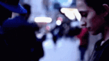 a blurry picture of a man standing in a crowded street .