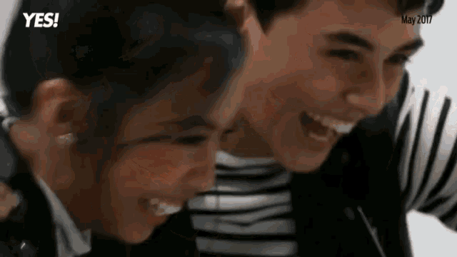 a man and a woman are laughing together and looking at each other .