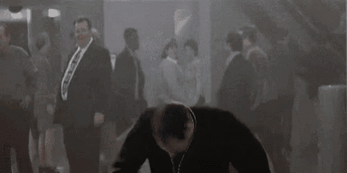 a priest is dancing in a crowded room while wearing a cross necklace .