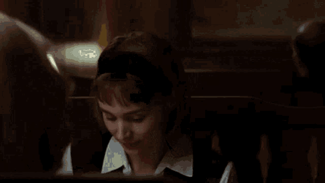 a woman is sitting in a dark room with the words " what a strange girl you are " above her