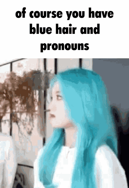 a woman with blue hair and pronouns is standing in front of a wall .